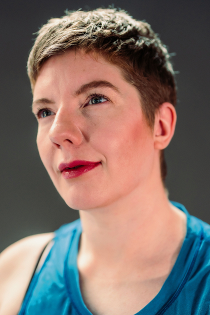 
	Laurel Lawson headshot. She is a white woman with cropped hair. Her chin is lifted and her gaze directed upwards with a slight smile; her blue eyes compliment her gauzy blue tank. Photo Robbie Sweeny
		